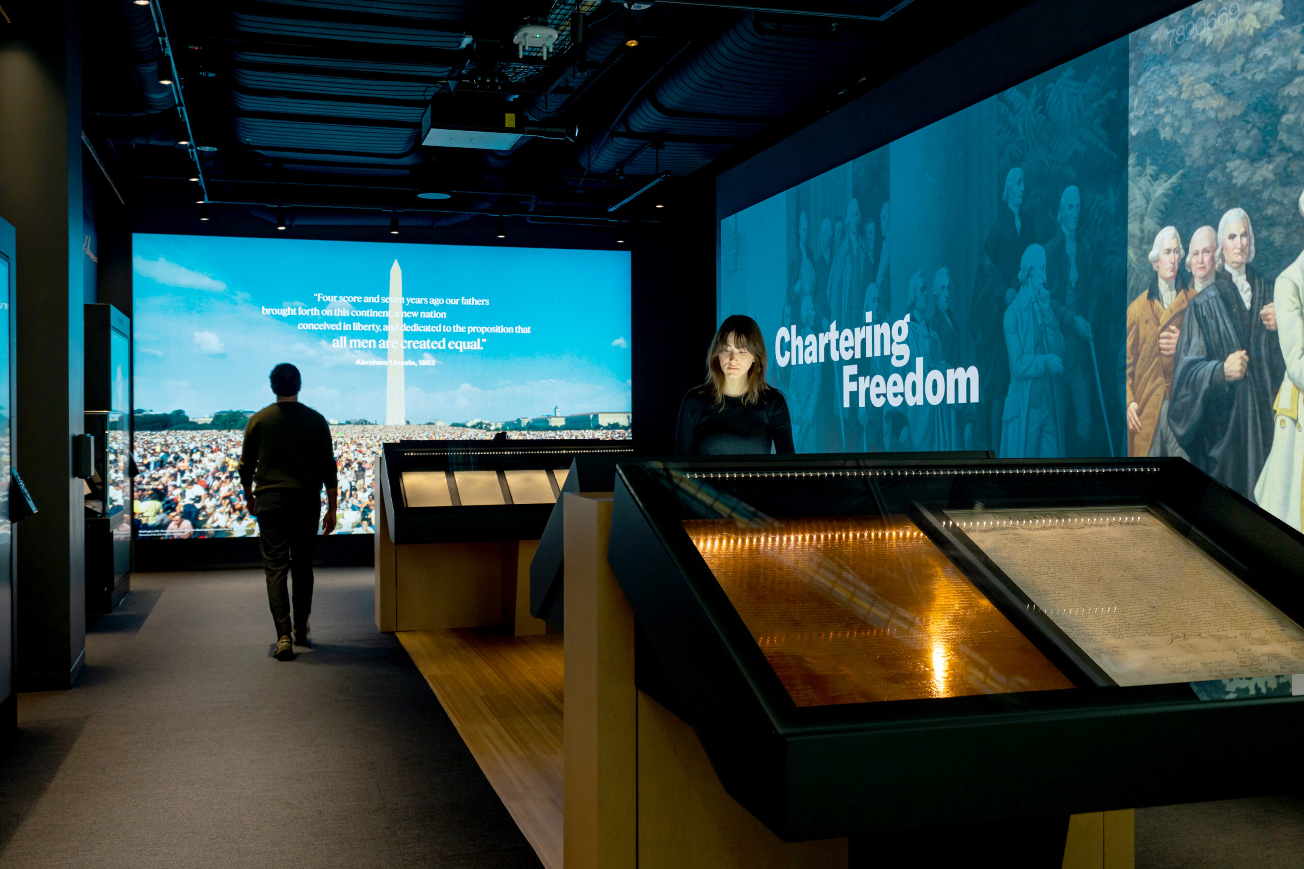 woman stands at interactive exhibit in front of screen that says Chartering Freedom
